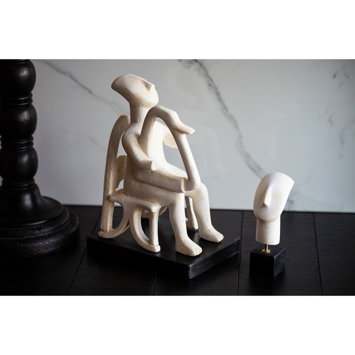 A Cycladic head sculpture next to a Cycladic harpist sculpture